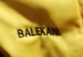 Balekani name embroidered in black on yellow fabric